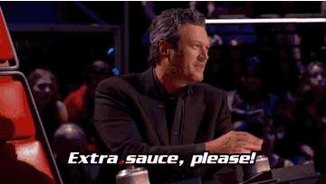 Blake Shelton, seated at a judge's panel, speaks animatedly with the caption "Extra sauce, please!" in the foreground