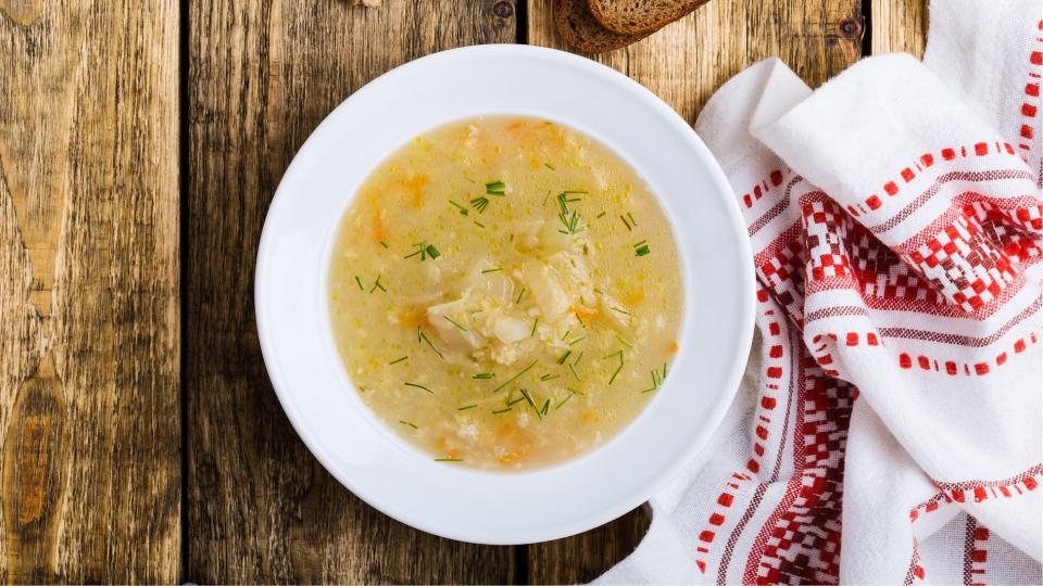 Cabbage Soup in ceramic bowl sitting on wooden table with tablecloth