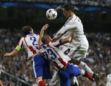 Real Madrid's Cristiano Ronaldo (R) goes for a header with Atletico Madrid's Miranda (C) and Diego Godin during their Champions League quarter-final second leg soccer match at the Santiago Bernabeu stadium in Madrid, April 22, 2015 REUTERS/Stringer