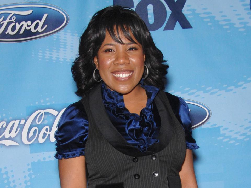 Melinda Doolittle wears a black vest and dark-blue silk shirt in front of "American Idol" background on red carpet