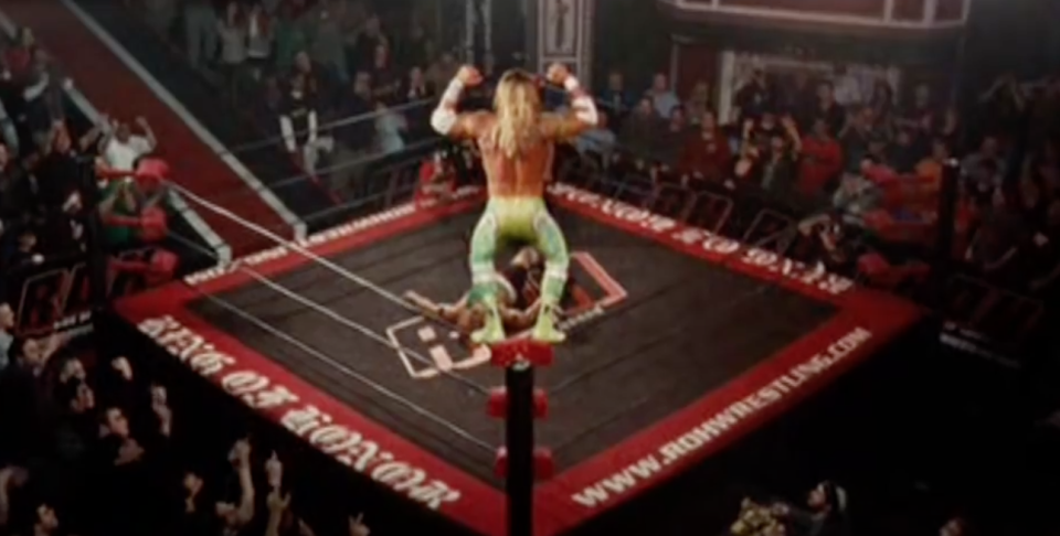 A man jumps from the top rope of a wrestling ring