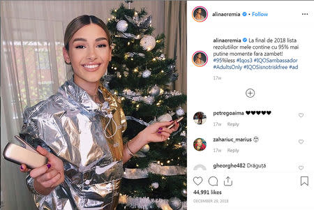 Alina Eremia, a Romanian actress and singer whose biography gives her age as 25, holds a gold-colored IQOS device in front of a Christmas tree as part of a campaign by Philip Morris International to market the device in an Instagram post December 29, 2018. Alina Eremia/Social Media via REUTERS