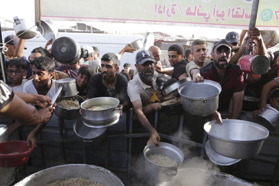 CORRECTS LOCATION TO KHAN YOUNIS - Palestinian men collect food aid ahead of the upcoming Eid al-Adha holiday in Khan Younis, Gaza Strip, Saturday, June 15, 2024. (AP Photo/Jehad Alshrafi)