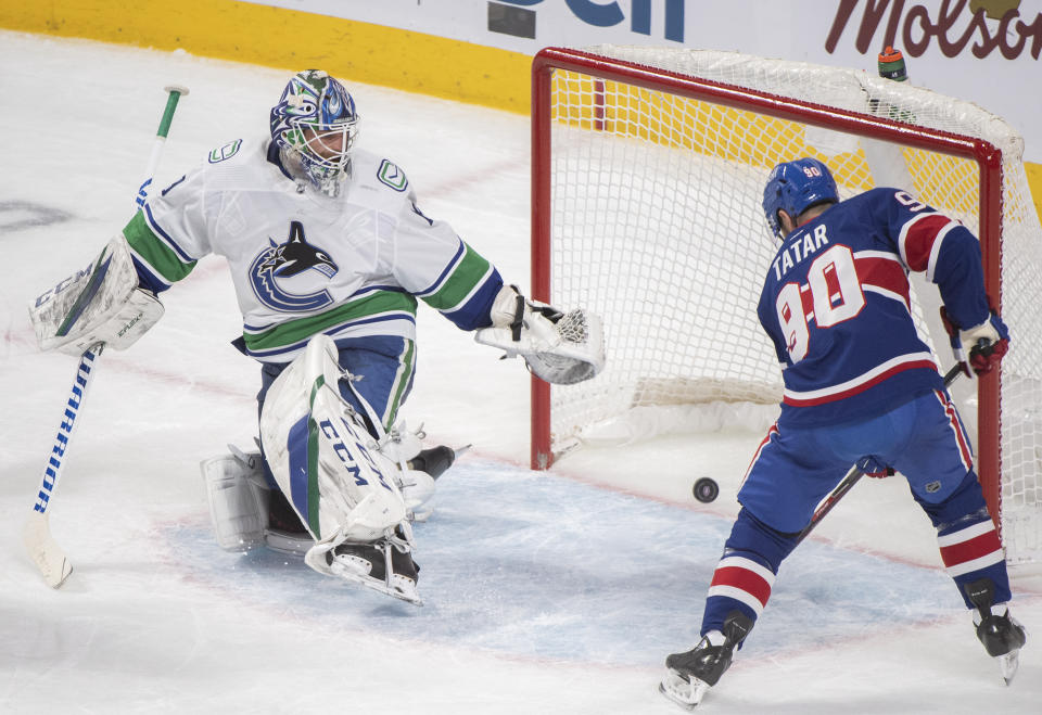 Montreal Canadiens' Tomas Tatar puts the puck in the net behind Vancouver Canucks goaltender Braden Holtby during the second period of an NHL hockey game Saturday, March 20, 2021, in Montreal. (Graham Hughes/The Canadian Press via AP)