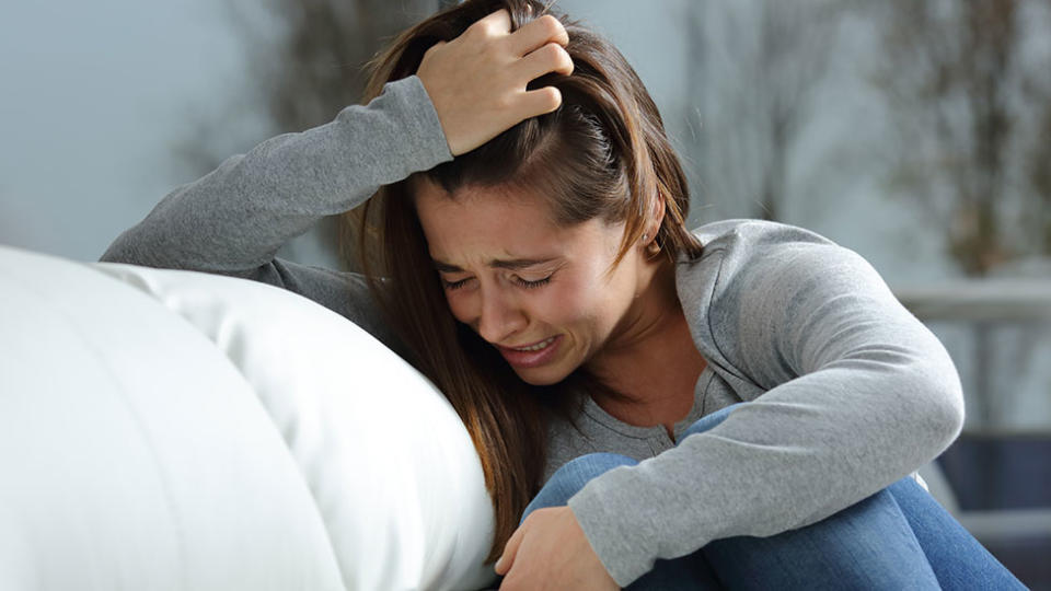 crying woman wearing jeans and a grey weater