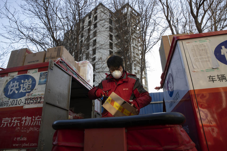 In this Tuesday, Feb. 18, 2020, photo, a delivery worker for Chinese e-commerce giant JD.com prepares for the morning round of deliveries from a distribution center in Beijing, China. JD and rivals including Pinduoduo, Miss Fresh and Alibaba Group's Hema are scrambling to fill a boom in orders while protecting their employees. E-commerce is one of the few industries to thrive after anti-virus controls starting in late January closed factories, restaurants, cinemas, offices and shops nationwide and extinguished auto and real estate sales. (AP Photo/Ng Han Guan)