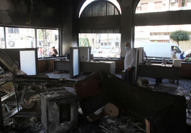 Man inspect interior of a bank after it was set ablaze during unrest overnight, in Tripoli