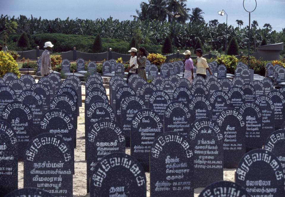 Tamil Tigers and civilians walk through a cemetery honouring Tamil separatists of the Liberation Tigers of Tamil Eelam January 1, 1994 in Jaffna, Sri Lanka.