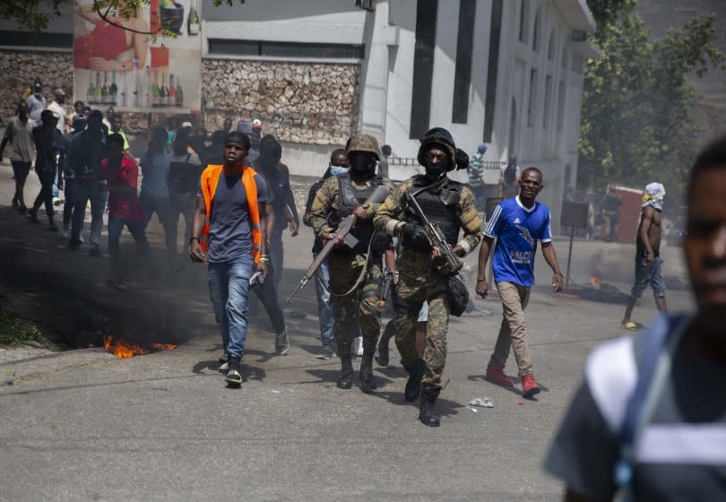 Police walk among protesters during a protest against the assassination of Haitian President Jovenel Moïse near the police station of Petion Ville in Port-au-Prince, Haiti, Thursday, July 8, 2021. Officials pledged to find all those responsible for the pre-dawn raid on Moïse's home early Wednesday in which the president was shot to death and his wife, Martine, critically wounded. (AP Photo/Joseph Odelyn)
