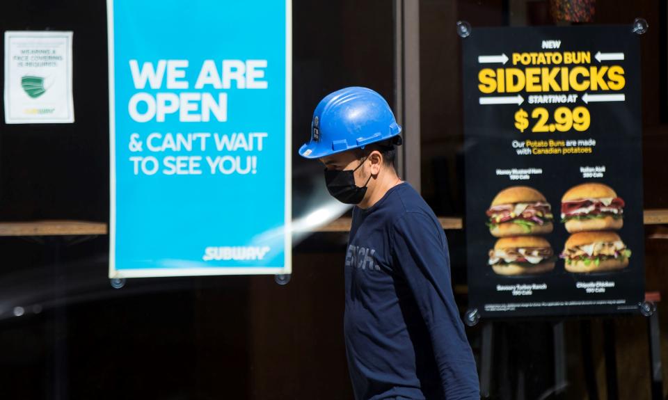 TORONTO, March 12, 2021 -- A worker wearing a face mask walks past a fast food restaurant with a 