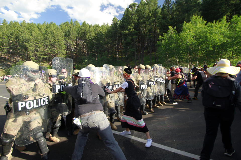 Protesters clash with a line of law enforcement officers in Keystone, S.D., on the road leading to Mount Rushmore ahead of President Donald Trump's visit to the memorial on Friday, July 3, 2020. (AP Photo/Stephen Groves)