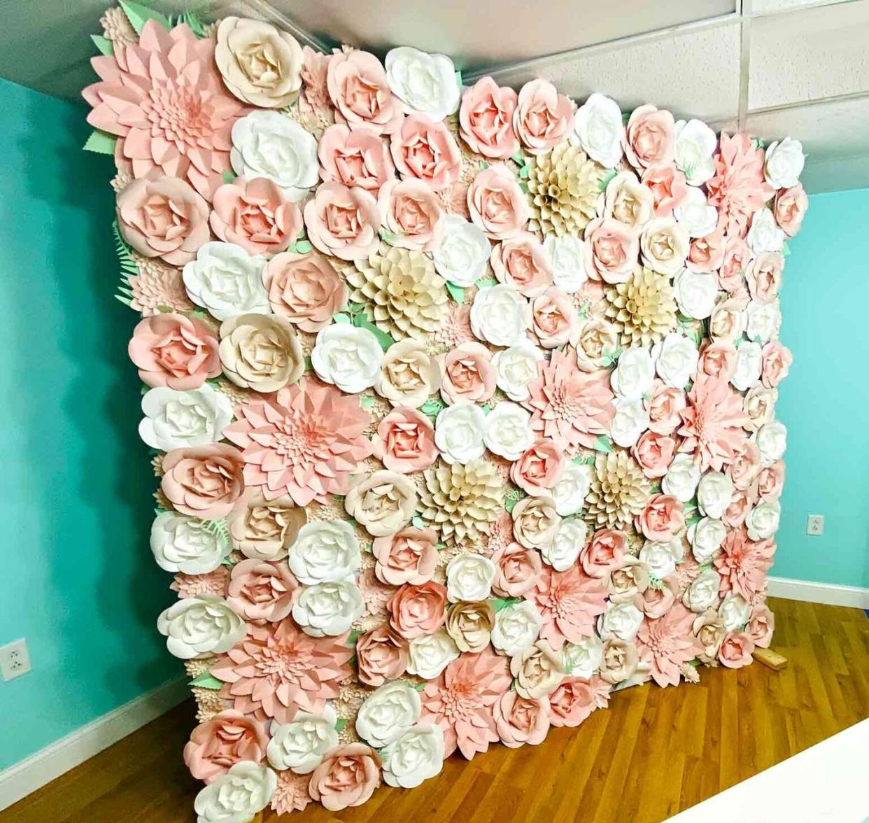 a room is dominated by a paper flower backdrop, a great baby shower idea