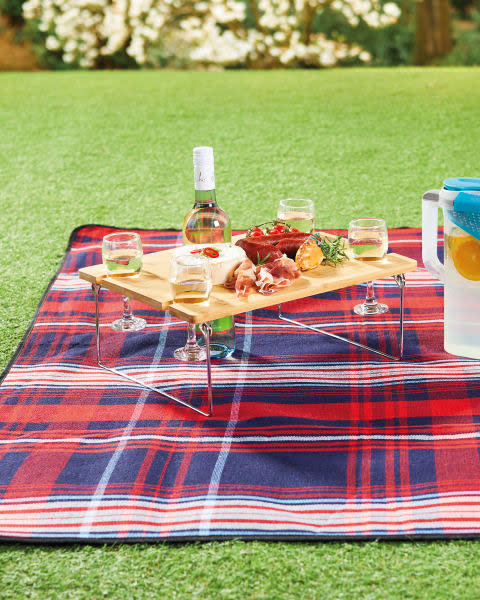 The Adi picnic table keeps your wine bottle and glasses safe, with room for snacks too. (Aldi)