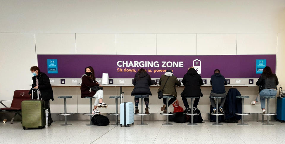 Los viajeros cargan sus teléfonos en el aeropuerto de Gatwick, mientras esperan la información sobre sus vuelos. (Photo by Gareth Fuller/PA Images via Getty Images)