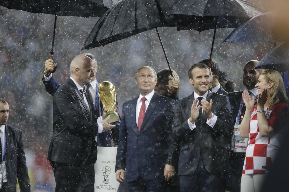 FILE - From left to right, FIFA President Gianni Infantino, Russia's President Vladimir Putin, France's President Emmanuel Macron and Croatia's President Kolinda Grabar-Kitarovic stand under the pouring rain during the awards ceremony after final match between France and Croatia at the 2018 soccer World Cup in the Luzhniki Stadium in Moscow, Russia, Sunday, July 15, 2018. (AP Photo/Natacha Pisarenko, File)