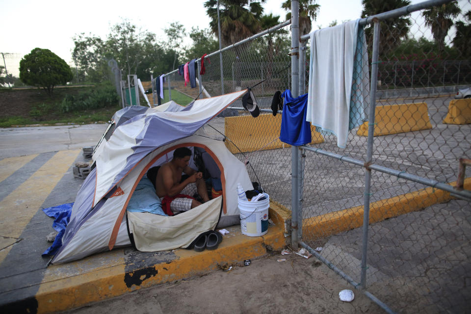 Honduran migrant Jose Antonio Sanchez Escalante, 24, who has been camping out for two months as he waits his turn to request asylum in the U.S., begins his day at the entrance to the Puerta Mexico bridge, in Matamoros, Mexico, Thursday, June 27, 2019. Hundreds of migrants from Central America, South America, the Caribbean and Africa have been waiting for their number to be called at the bridge in downtown Matamoros, to have the opportunity to request asylum. With the exception of a handful of migrants who had been there for months, authorities have prohibited camping and migrants have had to move to rented rooms and one distant private shelter.(AP Photo/Rebecca Blackwell)