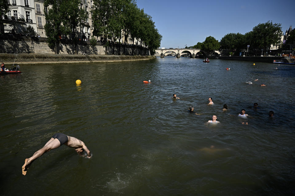 A local resident dives in the Seine, in Paris on July 17, 2024, after the mayor of Paris  swim in the river to demonstrate that it is clean enough to host the outdoor swimming events at the Paris Olympics later this month. Despite an investment of 1.4 billion euros ($1.5 billion) to prevent sewage leaks into the waterway, the Seine has been causing suspense in the run-up to the opening of the Paris Games on July 26 after repeatedly failing water quality tests. But since the beginning of July, with heavy rains finally giving way to sunnier weather, samples have shown the river to be ready for the open-water swimming and triathlon -- and for 65-year-old Hidalgo. (Photo by JULIEN DE ROSA / AFP) (Photo by JULIEN DE ROSA/AFP via Getty Images)