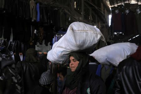 A woman holds a bag on her head at a souk in Manbij city, Syria December 29, 2018. Picture taken December 29, 2018. REUTERS/Rodi Said