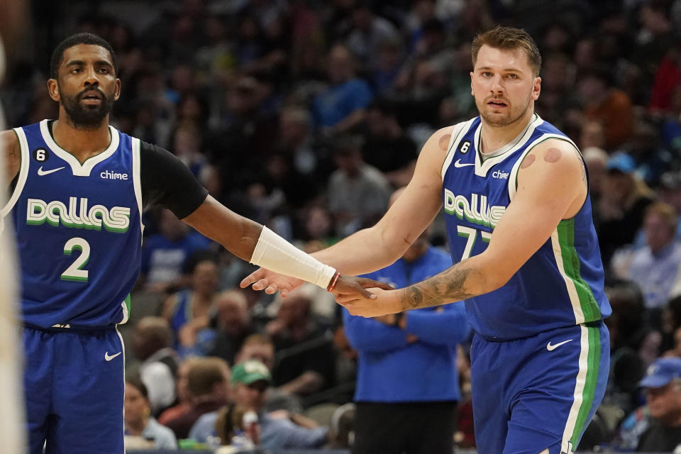 Dallas Mavericks guards Kyrie Irving (2) and Luka Doncic (77) reach to each other during the second half of an NBA basketball game against the Charlotte Hornets in Dallas, Friday, March 24, 2023. (AP Photo/LM Otero)