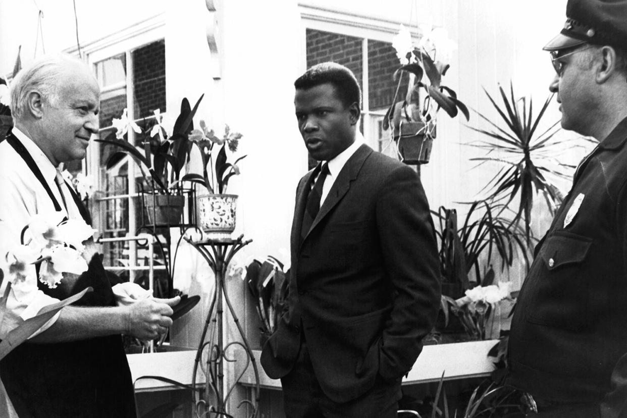 Sidney Poitier and Rod Steiger stand talking to an unknown actor wearing an apron in a scene from the film 'In The Heat Of The Night', 1967.
