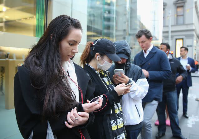 Apple fangirls and fanboys fiddle with their working phones as they queue to buy new phones. Source: Getty