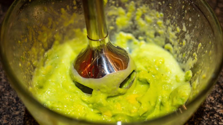 Mixing avocado and milk with immersion blender