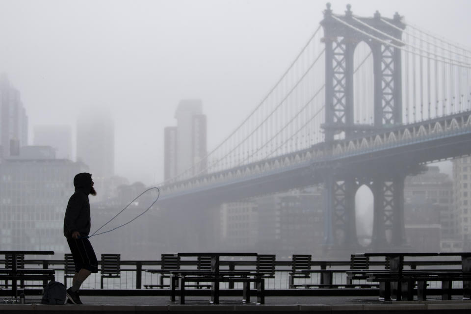 A Men is framed by the Manhattan bridge as he exercises below the FDR drive in Lower Manhattan, Sunday, March 29, 2020. The new coronavirus causes mild or moderate symptoms for most people, but for some, especially older adults and people with existing health problems, it can cause more severe illness or death. (AP Photo/Mary Altaffer)