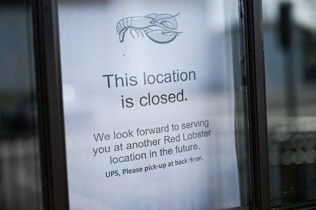 Sign on a window with a lobster logo stating, "This location is closed. We look forward to serving you at another Red Lobster location in the future. UPS, please pick up at back door."