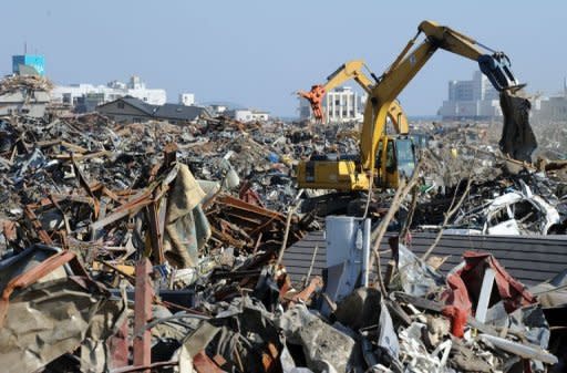 Heavy machinery removes tsunami devastation in Rikuzentakata city, Iwate prefecture. The impact of Japan's earthquake and nuclear crisis rippled through the economy Wednesday as the government downgraded its outlook and Toyota announced more temporary plant shutdowns overseas