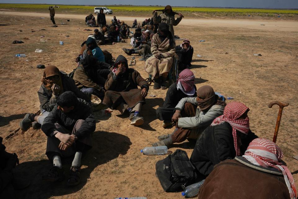 Men wait to be screened after being evacuated out of the last territory held by Islamic State militants outside Baghouz, Syria, Wednesday, March 6, 2019. Since Friday, IS has put up desperate resistance to renewed pounding by the U.S.-backed Syrian Democratic Forces aiming to take the tiny pocket on the Euphrates River near the Iraqi border.(AP Photo/Andrea Rosa)