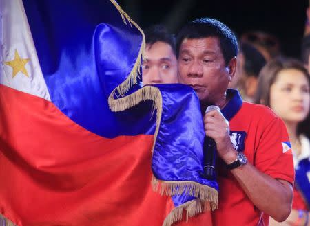 Rodrigo 'Digong' Duterte holds a Philippine flag while addressing his supporters during a "Miting de Avance" (last political campaign rally) before national elections at Rizal park in metro Manila, Philippines May 7, 2016. REUTERS/Romeo Ranoco