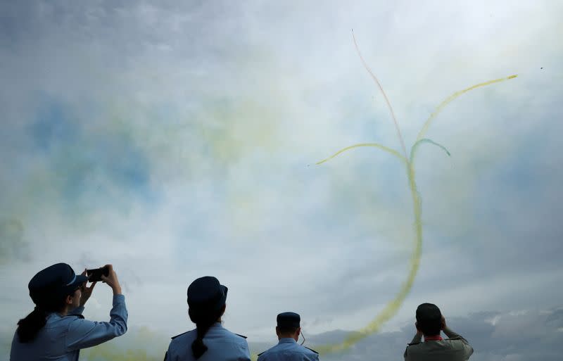 Members of China's People's Liberation Army Air Force (PLAAF) watch an aerial display by their Ba Yi Aerobatics team during a media preview of the Singapore Airshow in Singapore