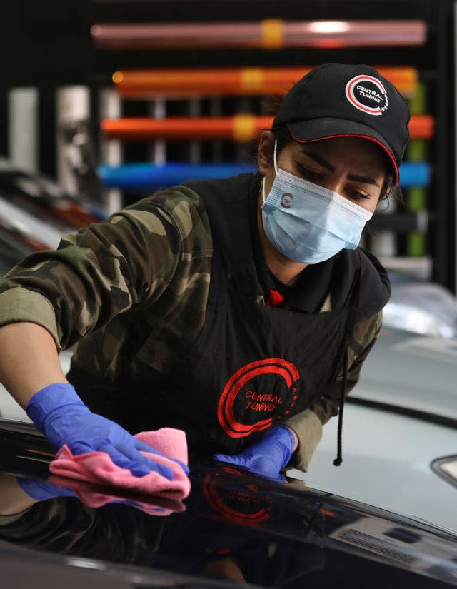 Female Iranian car detailer Maryam Roohani polishes a car at a detailing shop in Tehran