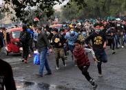 Iraqi demonstrators run away for a cover during ongoing anti-government protests in Baghdad