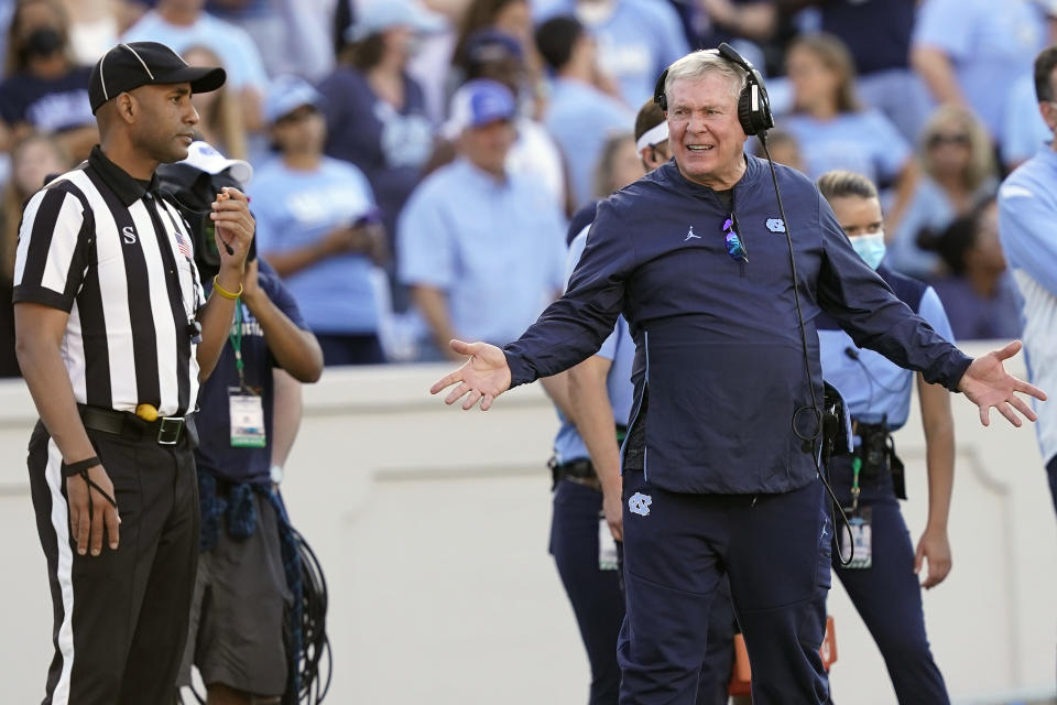 North Carolina head coach Mack Brown, right, speaks with an official during the first half of an NCAA college football game against Miami in Chapel Hill, N.C., Saturday, Oct. 16, 2021. (AP Photo/Gerry Broome)