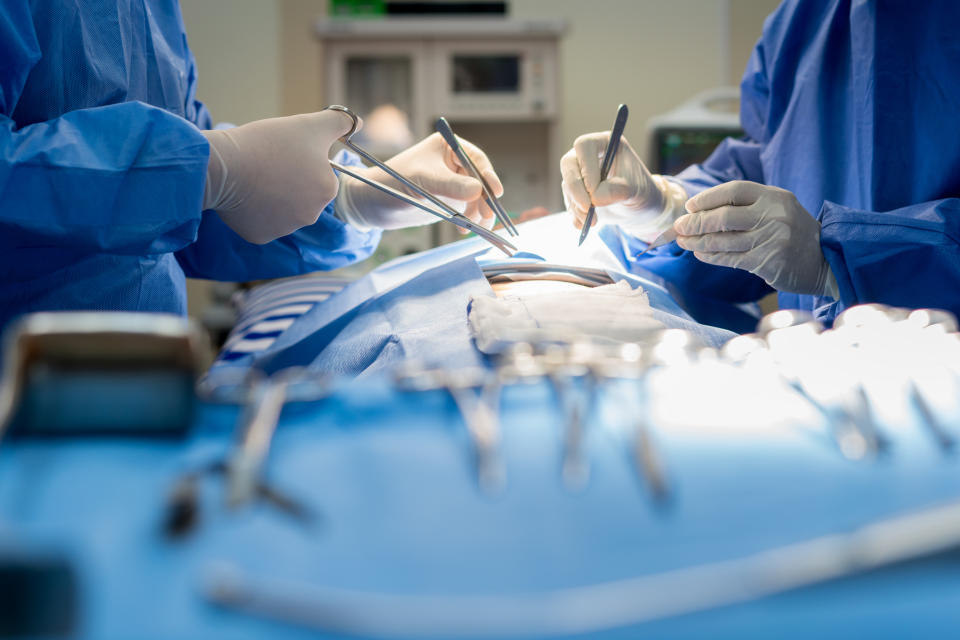 Surgeons performing a surgical procedure in an operating room, with various medical instruments visible in the foreground