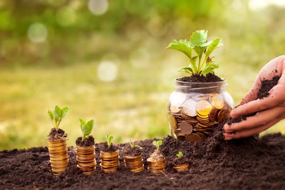 A hand planting a jar of coins, next to rising stacks of coins with plants on top