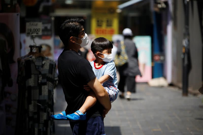 A man holds his son as they shop at Myeongdong shopping district which is nearly empty amid the coronavirus disease (COVID-19) pandemic in Seoul