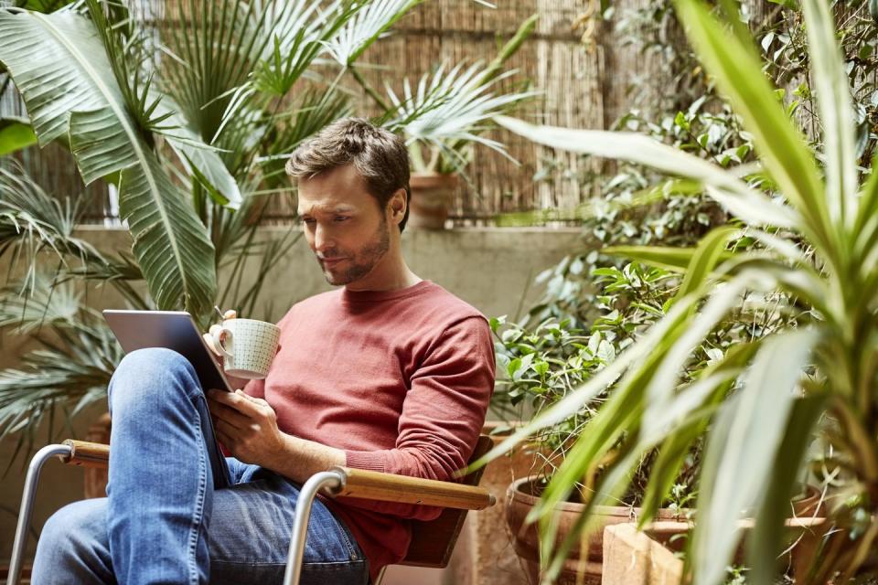 man using digital tablet while having coffee