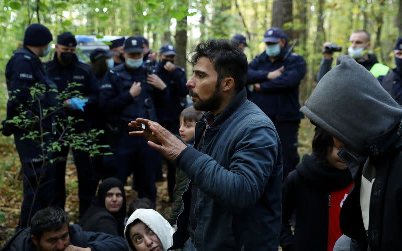 FILE PHOTO: Iraqi migrants talk to NGO Grupa Granica's representatives as they are surrounded by border guards and police officers after they crossed the Belarusian-Polish border during the ongoing migrant crisis, in Hajnowka