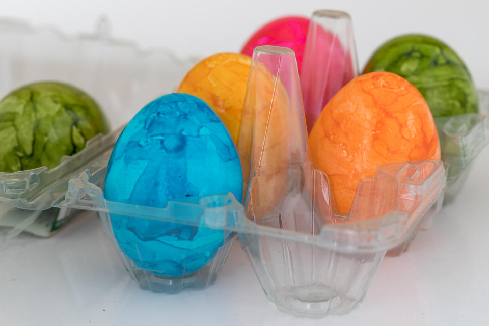 six colorful easter eggs in a box of plastic bought in a supermarket