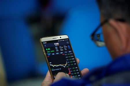 An investor checks stock information on a mobile phone at a brokerage house in Shanghai, China February 9, 2018. REUTERS/Aly Song