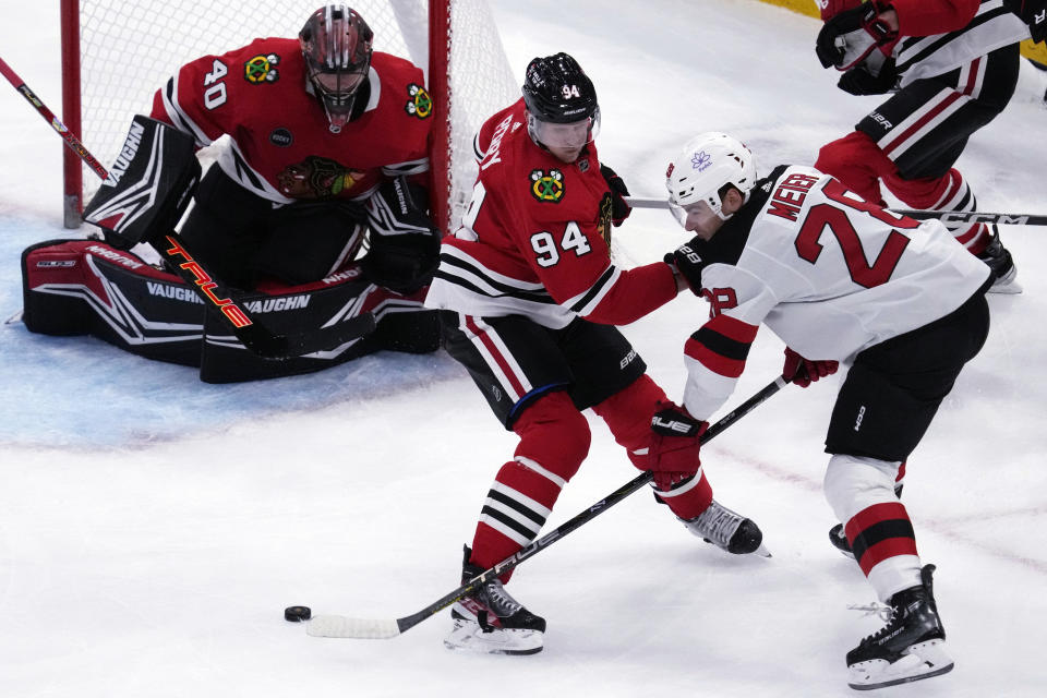 New Jersey Devils right wing Timo Meier, right, shoots against Chicago Blackhawks right wing Corey Perry as goaltender Arvid Soderblom, left, looks on during the first period of an NHL hockey game in Chicago, Sunday, Nov. 5, 2023. (AP Photo/Nam Y. Huh)