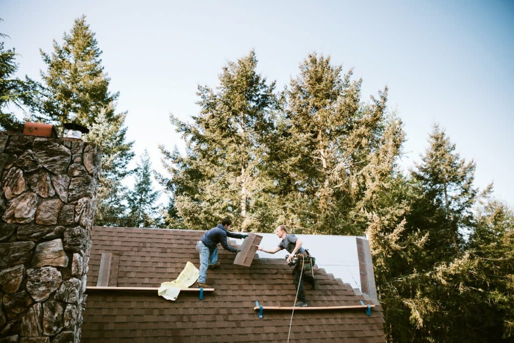 Two people work on replacing a roof. 