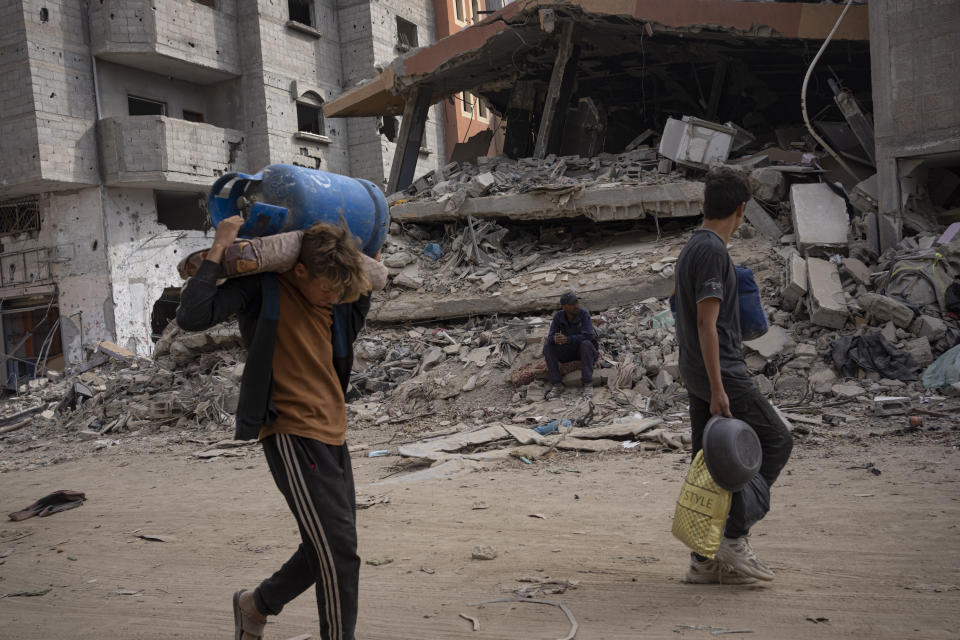 Palestinians walk through the destruction in the wake of an Israeli air and ground offensive in Khan Younis, southern Gaza Strip, Monday, April 8, 2024. Israel says it has withdrawn its last ground troops from the city, ending a four-month operation. (AP Photo/Fatima Shbair)