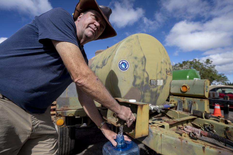 Jim Rensberger fills up a water jug from a water buffalo at Kula distribution hub on Wednesday, Sept. 27, 2023, in Kula, Hawaii. (AP Photo/Mengshin Lin)