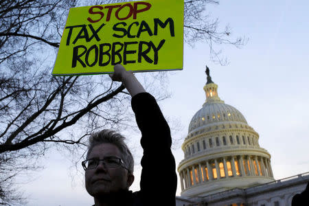 REFILE - CORRECTING GRAMMAR A demonstrator holds a sign outside the U.S. Capitol to protest the Republican tax plan as it works through the Senate in Washington November 30, 2017. REUTERS/James Lawler Duggan