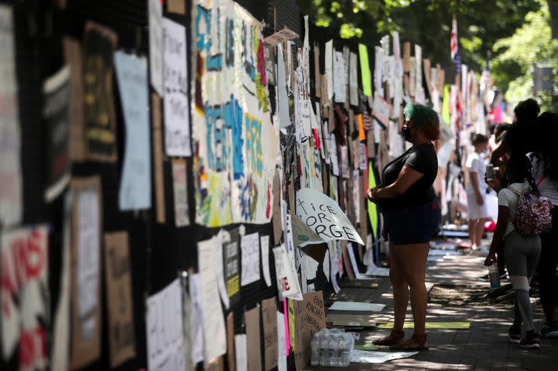 FILE PHOTO: People gather to view protest signs now affixed to the fence around Lafayette Square at the scene where protesters clashed with police near the White House in Washington