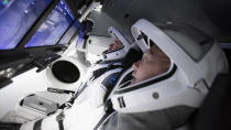 In this Thursday, March 19, 2020 photo made available by SpaceX, astronauts Doug Hurley, foreground, and Bob Behnken work in SpaceX's flight simulator at the Kennedy Space Center in Cape Canaveral, Fla., as SpaceX teams in Firing Room 4 at Kennedy Space Center and the company's Mission Control in Hawthorne, Calif., along with NASA flight controllers in Mission Control Houston, run a full simulation of launch and docking of the Crew Dragon spacecraft. (SpaceX via AP)