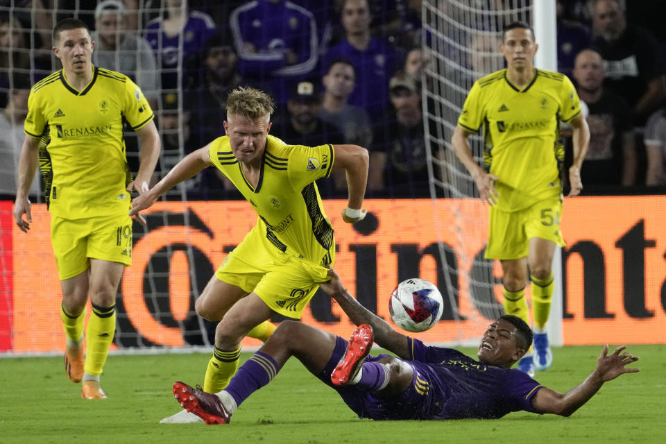 Orlando City midfielder Wilder Cartagena, lower right, grabs the jersey of Nashville SC forward Sam Surridge, center, as he falls trying to get position on the ball during the first half of an MLS playoff soccer match, Monday, Oct. 30, 2023, in Orlando, Fla. (AP Photo/John Raoux)